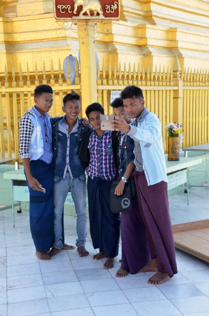 Young men taking selfies at a pagoda in Myanmar 